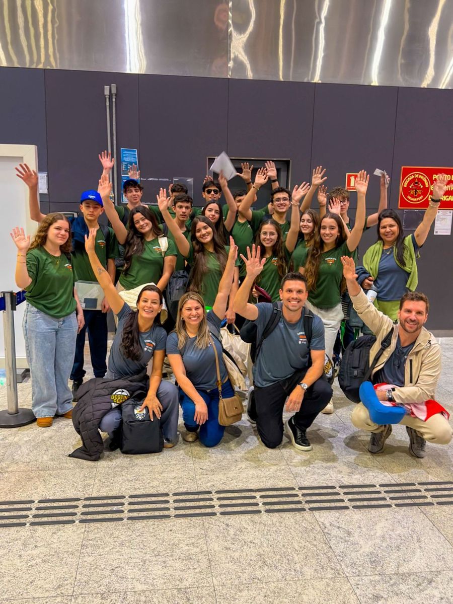 Grupo do Summer Camp, com os líderes, acenando no aeroporto com as camisetas verdes do programa